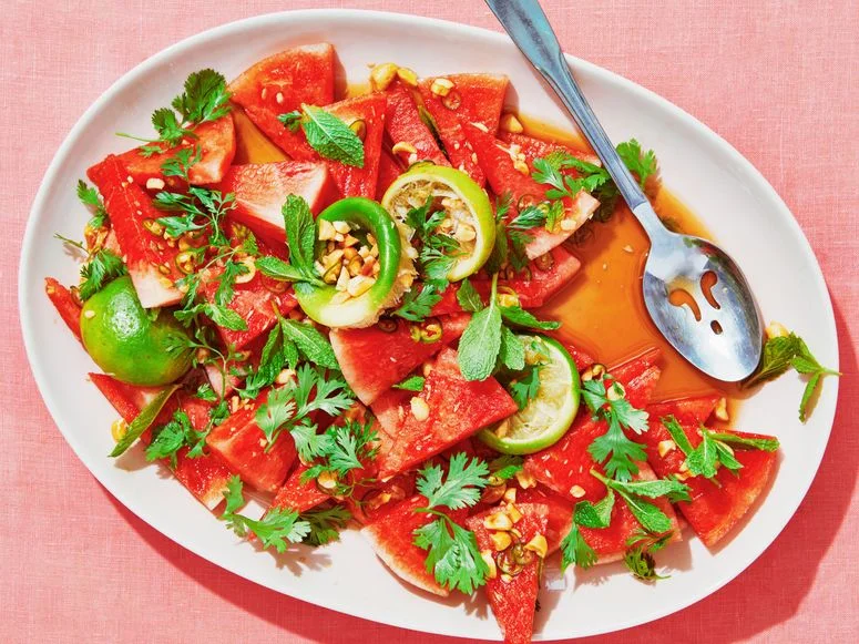 Watermelon cut into triangles crushed peanuts and limes tossed in fish sauce lime juice brown sugar and salt and topped...