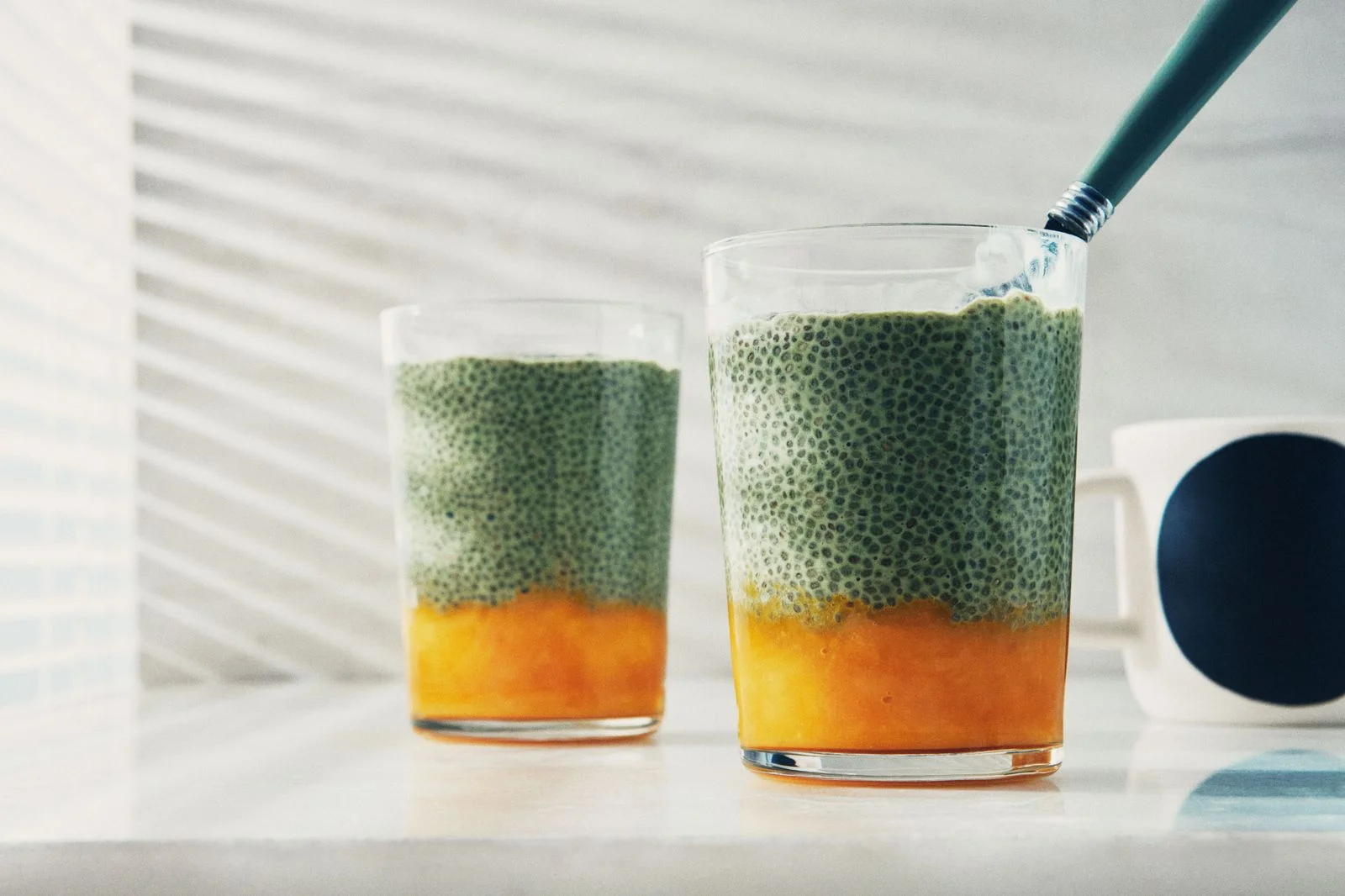 Two glasses filled with matcha chia seed pudding and mango pure.