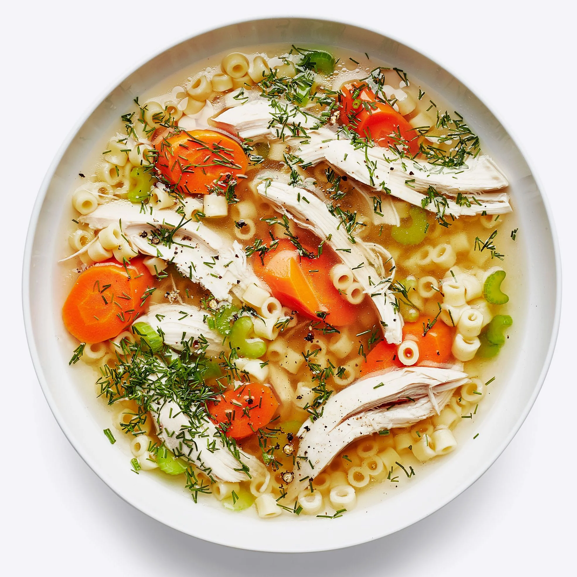 Bowl of chicken noodle soup with shredded chicken ditalini carrots celery and fresh dill.