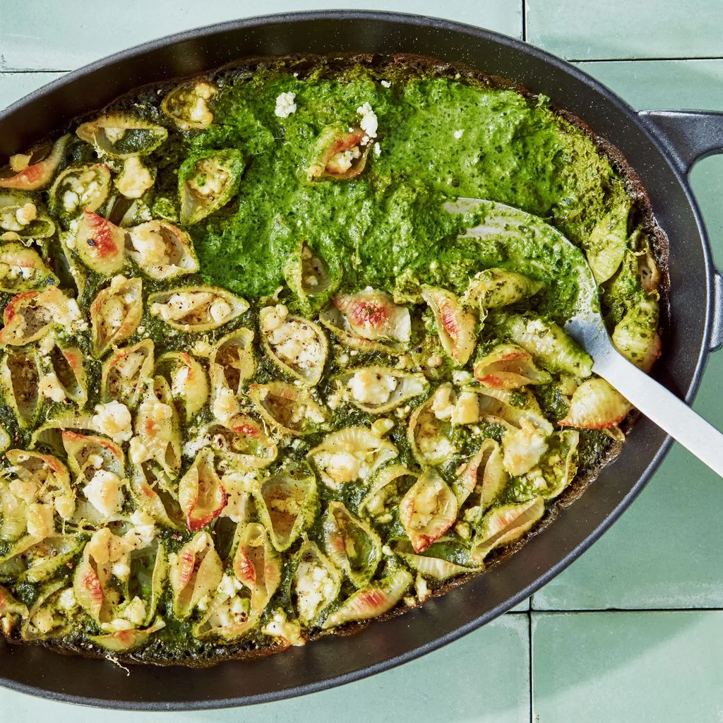 Shell pasta baked with crumbled feta in a braising dish on a bed of pured kale.
